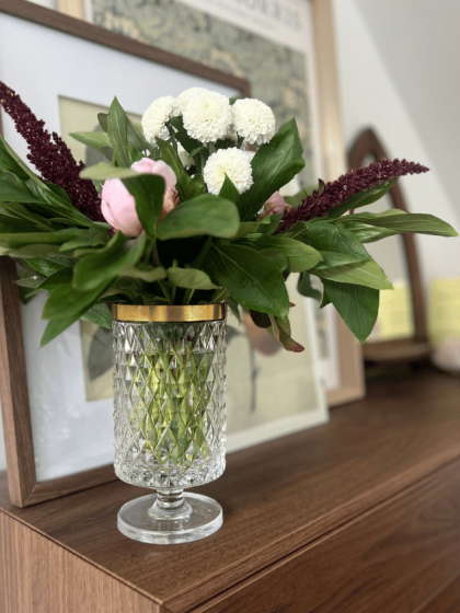 Kristallen vaas met gouden rand gevuld met kleurrijk boeket bloemen
