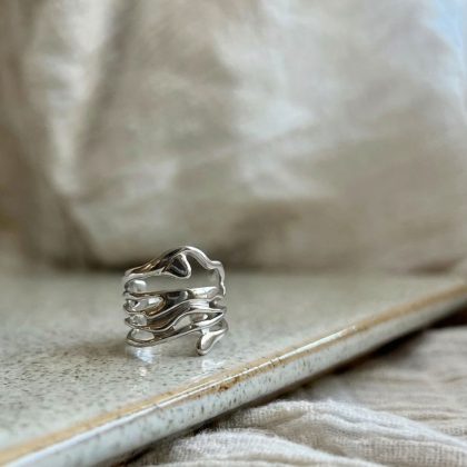 Zilvere drip ring, gepresenteerd op een natuurstenen plateau