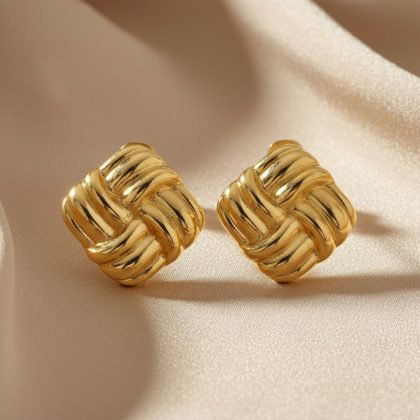 Goudkleurige statement knopoorbellen, product foto, liggend op satijn stof